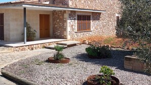 A two-story stone house with a tiled roof, a satellite dish, and a gravel driveway. - Modern house with large pool  (Búger)