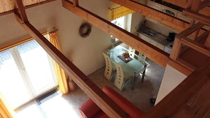 A wooden interior with a dining area, kitchen, and a view of the outside.