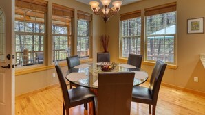 Un coin repas comprenant une table ronde en verre, six chaises et un lustre.