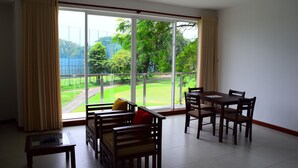 A room with a large window, a dining table with chairs, and a sofa with cushions. - The Green' Apartments (Colombo)