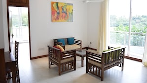 A spacious living room with a sofa, two armchairs, a coffee table, and a painting on the wall. - The Green' Apartments (Colombo)