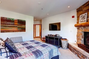 Ein Schlafzimmer mit einem Bett, einem Fernseher, einem Kamin und einem Wandbild.