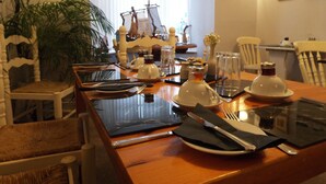 Una mesa de comedor preparada con platos, cubiertos y vasos, rodeada de sillas.