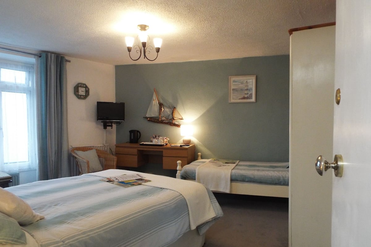 A hotel room with two beds, a desk, a chair, a television, and a wardrobe.
