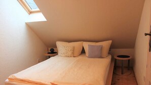 A small, cozy bedroom with a sloped ceiling, a single bed, two bedside tables, and a skylight. - Ferienhaus Windspiel (Lübbenau/Spreewald)