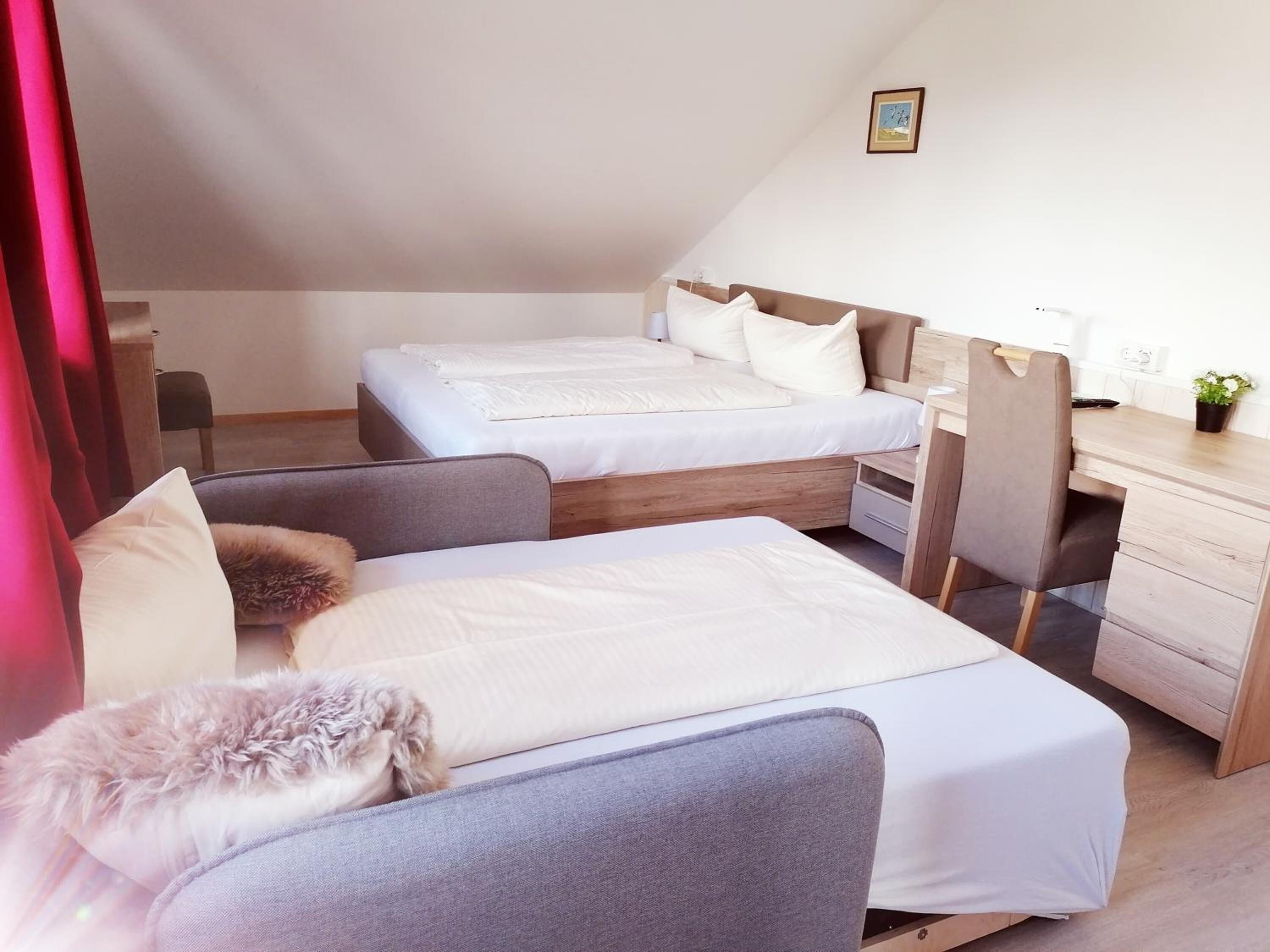 A bedroom with two beds, a desk, and a chair.