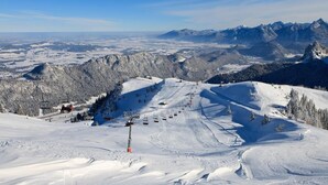 Een skigebied met een stoeltjeslift, besneeuwde hellingen en een bergachtige achtergrond.