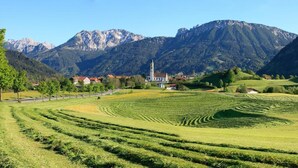 Een landelijk landschap met terrassen, een kerk en bergen op de achtergrond.