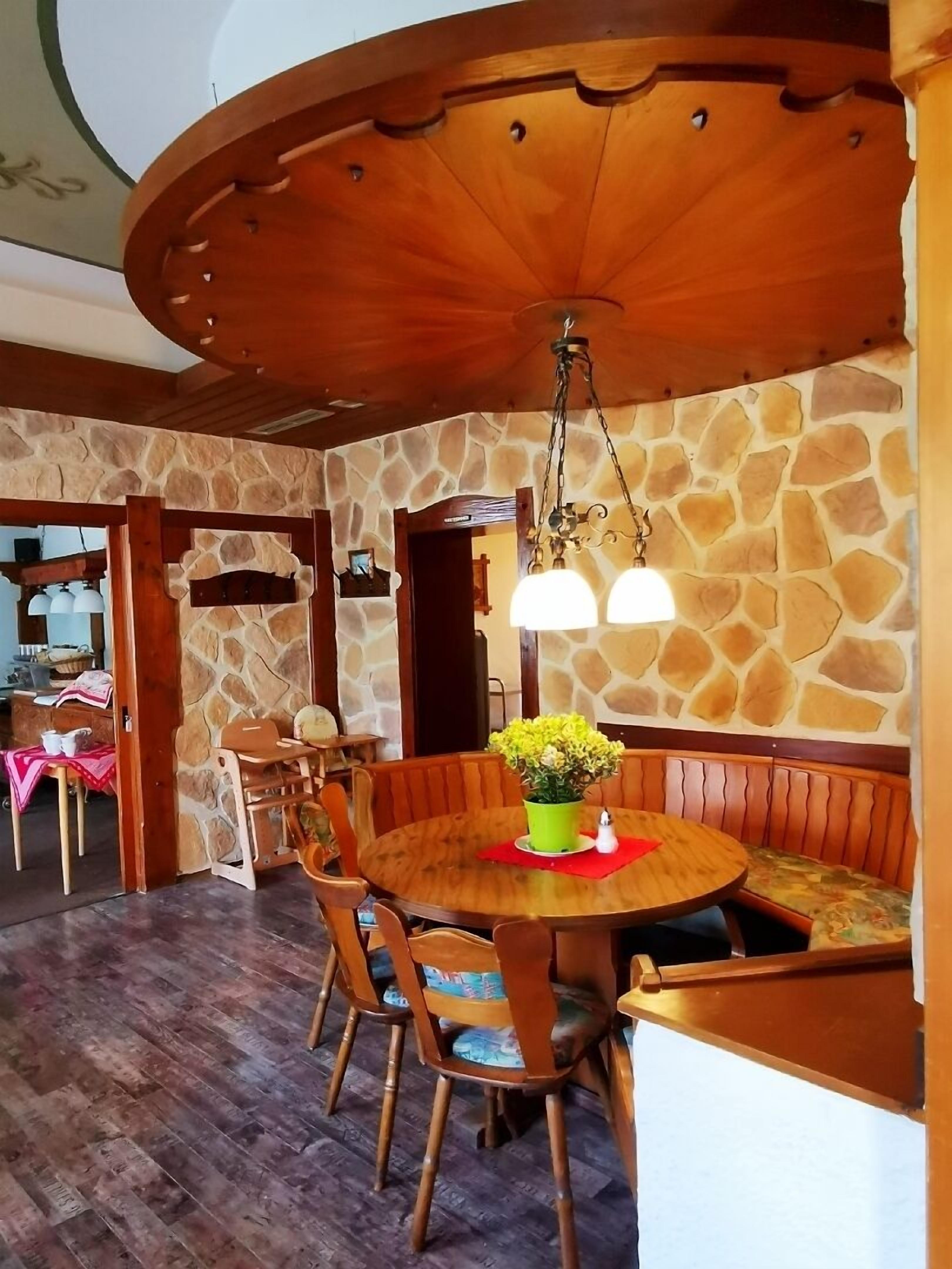 Ein Essbereich mit einem runden Holztisch, gepolsterten Bänken und einer Wand aus Stein.