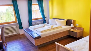Een slaapkamer met een bed, een nachtkastje, een stoel en een raam met gordijnen.