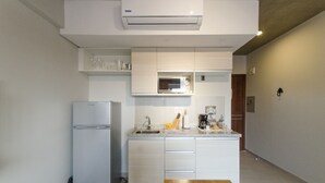 A compact kitchen with a built-in microwave, a sink, and a refrigerator. - Soho Style Moderno Studio las Mercedes (Asunción)