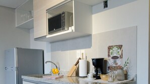 A modern kitchen with a built-in microwave, a refrigerator, and a coffee maker on the countertop. - Soho Style Moderno Studio las Mercedes (Asunción)