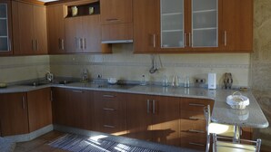 A kitchen with wooden cabinets, a granite countertop, and a built-in stove. - Rustic house with sea views (Carnota)