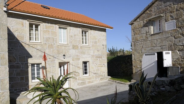 A stone building with a red-tiled roof, a small porch, and a door with a white shutter. - Rustic house with sea views (Carnota)