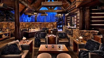 A cozy, rustic interior with stone walls, wooden furniture, and a stone fireplace.
