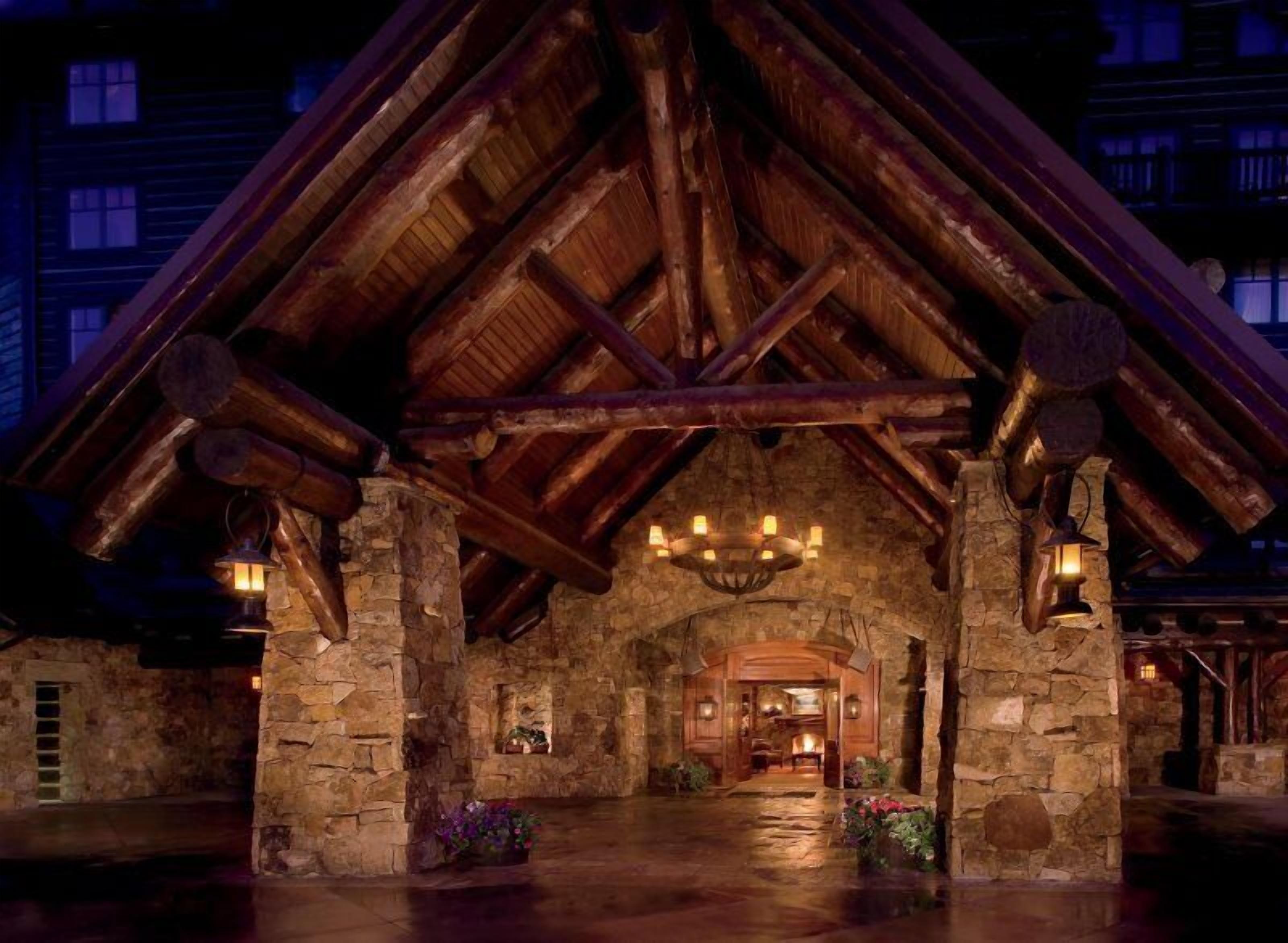 A rustic stone building with a wooden roof and a central chandelier.