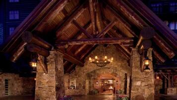 A rustic stone building with a wooden roof and a central chandelier.