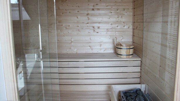 A sauna with wooden walls and a glass door. - Ferienwohnung Scheune (Lübbenau/Spreewald)