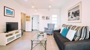 A living room with a TV, a glass coffee table, a sofa, and a chair. - Apartment Casa Nova (Carvoeiro)