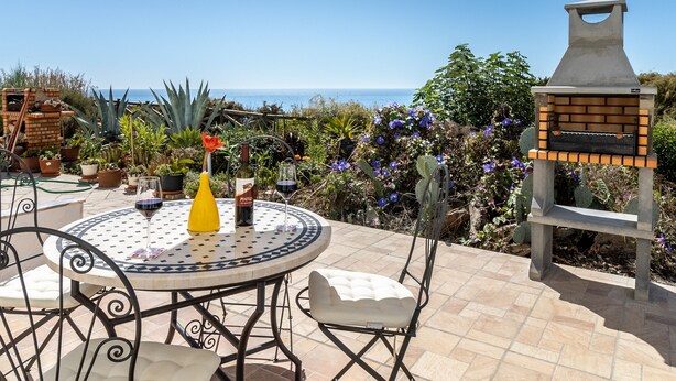 A patio with a round table, chairs, a grill, and potted plants. - Apartment Casa Nova (Carvoeiro)