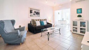 A living room with a sofa, armchair, and coffee table, a cabinet with dishes, and a framed picture on the wall. - Apartment Casa Nova (Carvoeiro)