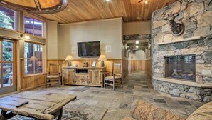 A cozy interior with a stone fireplace, wooden furniture, and a mounted deer head. - 1 Bedroom Plus Murphy Mountain Condo in River Run Village With Mountain Views and Walking Distance to Ski Slopes (Keystone)