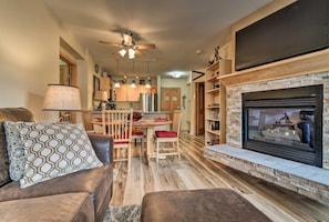 A modern living room with a fireplace, a dining area, and a kitchen.