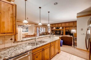 A kitchen with wooden cabinets, granite countertops, and pendant lighting. - Ski In 3 Bedroom at Chateaux Dumont Keystone (Keystone)