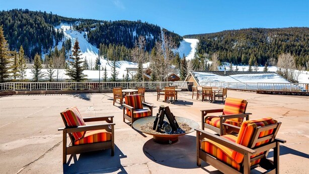 An outdoor seating area with chairs and a fire pit, overlooking a snowy mountain landscape. - Ski In 3 Bedroom at Chateaux Dumont Keystone (Keystone)