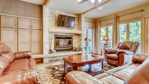A spacious living room with leather sofas, a fireplace, a television, and a ceiling fan. - Ski In 3 Bedroom at Chateaux Dumont Keystone (Keystone)