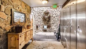 A stone-walled bathroom with a wooden vanity, a mirror, and a shower area. - Ski In 3 Bedroom at Chateaux Dumont Keystone (Keystone)