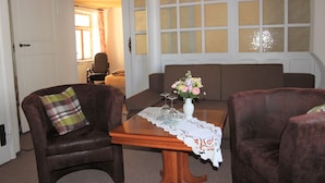 A cozy living room with a wooden table, two brown armchairs, a sofa, and a vase with flowers. - Ferienwohnung Brunnenblick (Lübbenau/Spreewald)