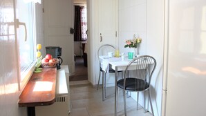 A small kitchen with a wooden counter, a sink, and a window. There is a table with chairs and a vase with flowers. - Ferienwohnung Brunnenblick (Lübbenau/Spreewald)