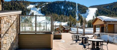 A patio area with outdoor seating and a view of a snowy mountain.