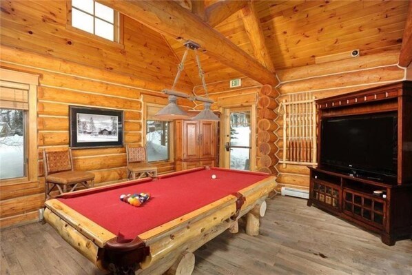 Une cabane en bois équipée d’une table de billard, d’un téléviseur et d’une cheminée.