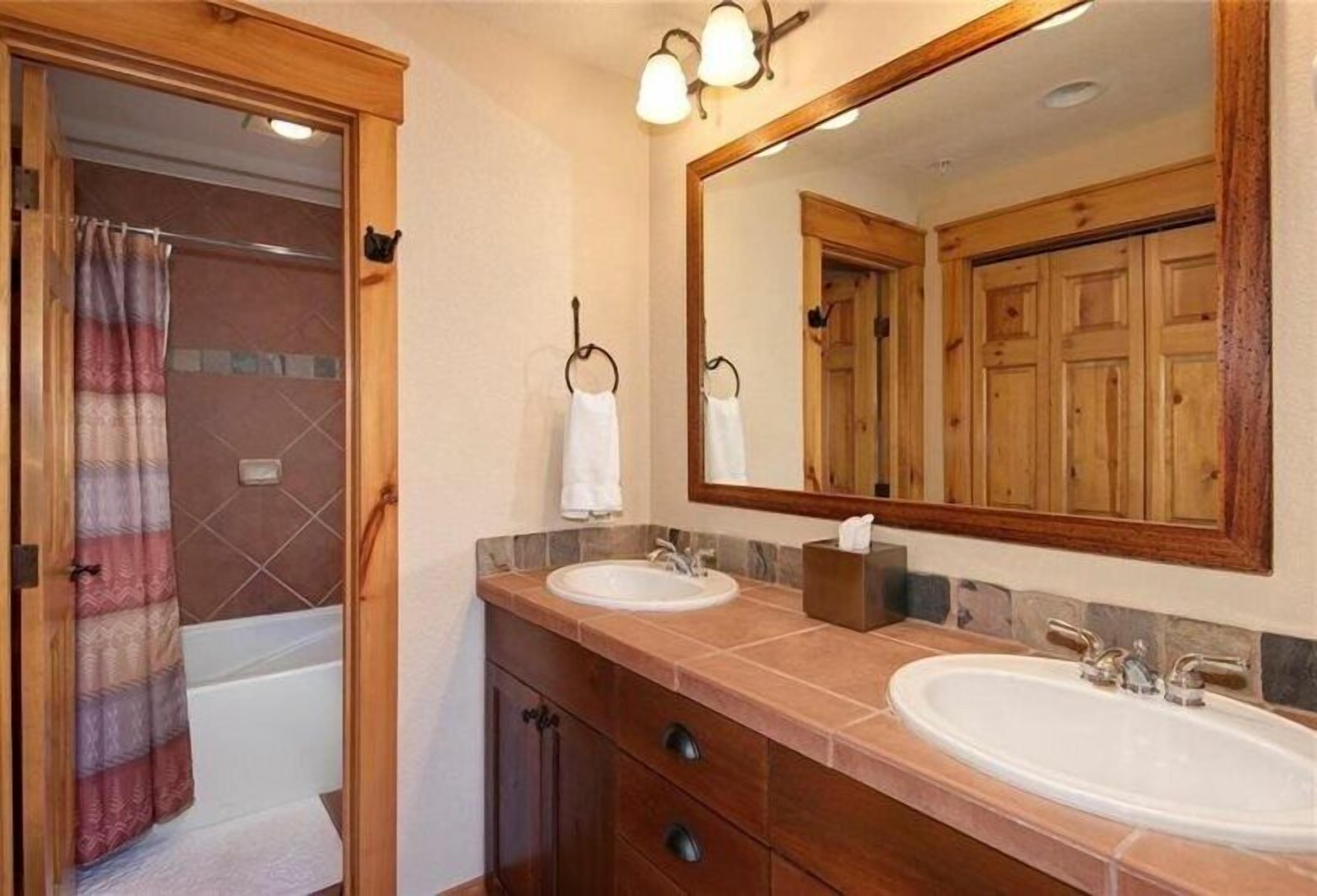 Une salle de bain avec deux lavabos, un miroir et une douche.