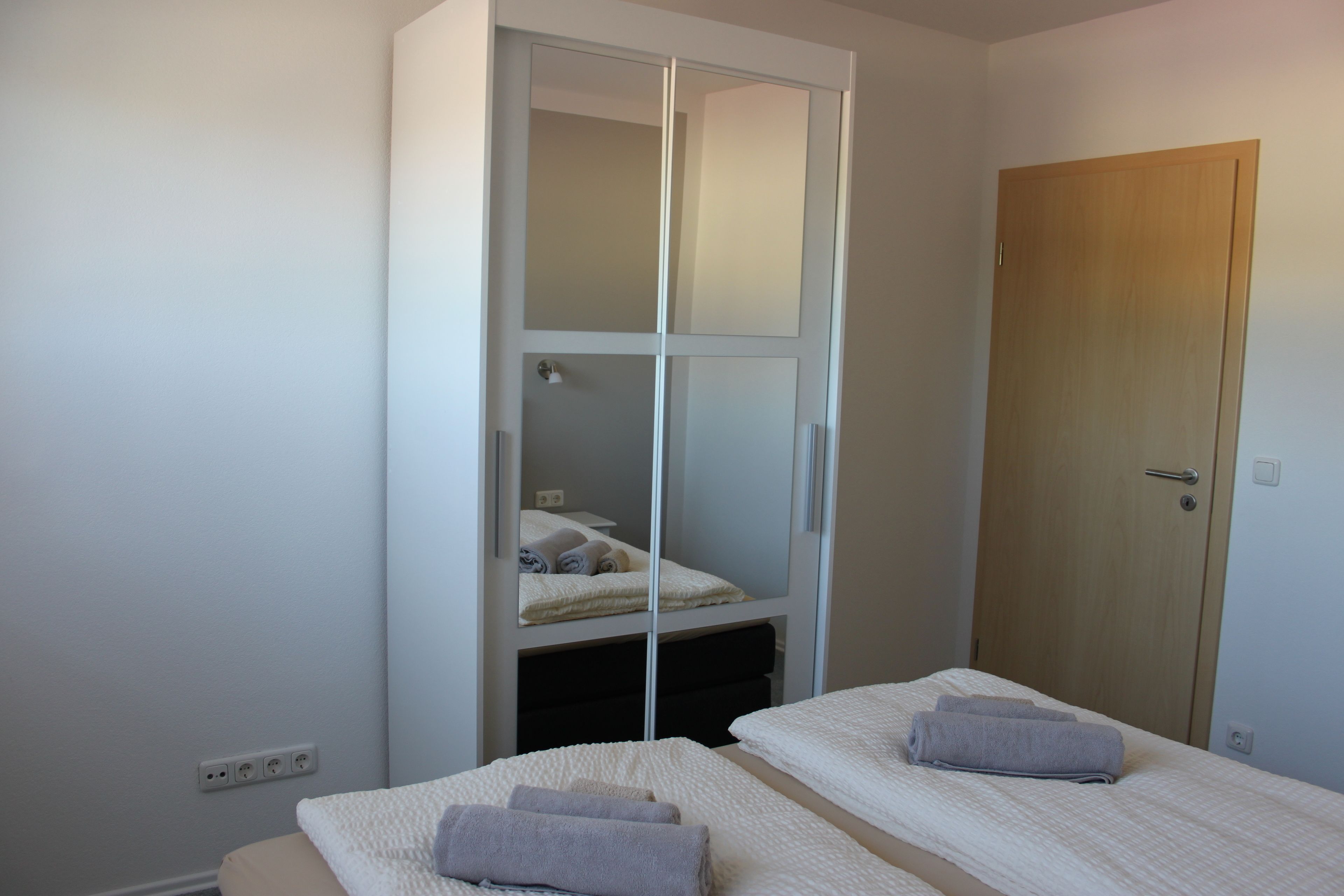 A bedroom with two single beds, a wardrobe, and a door.