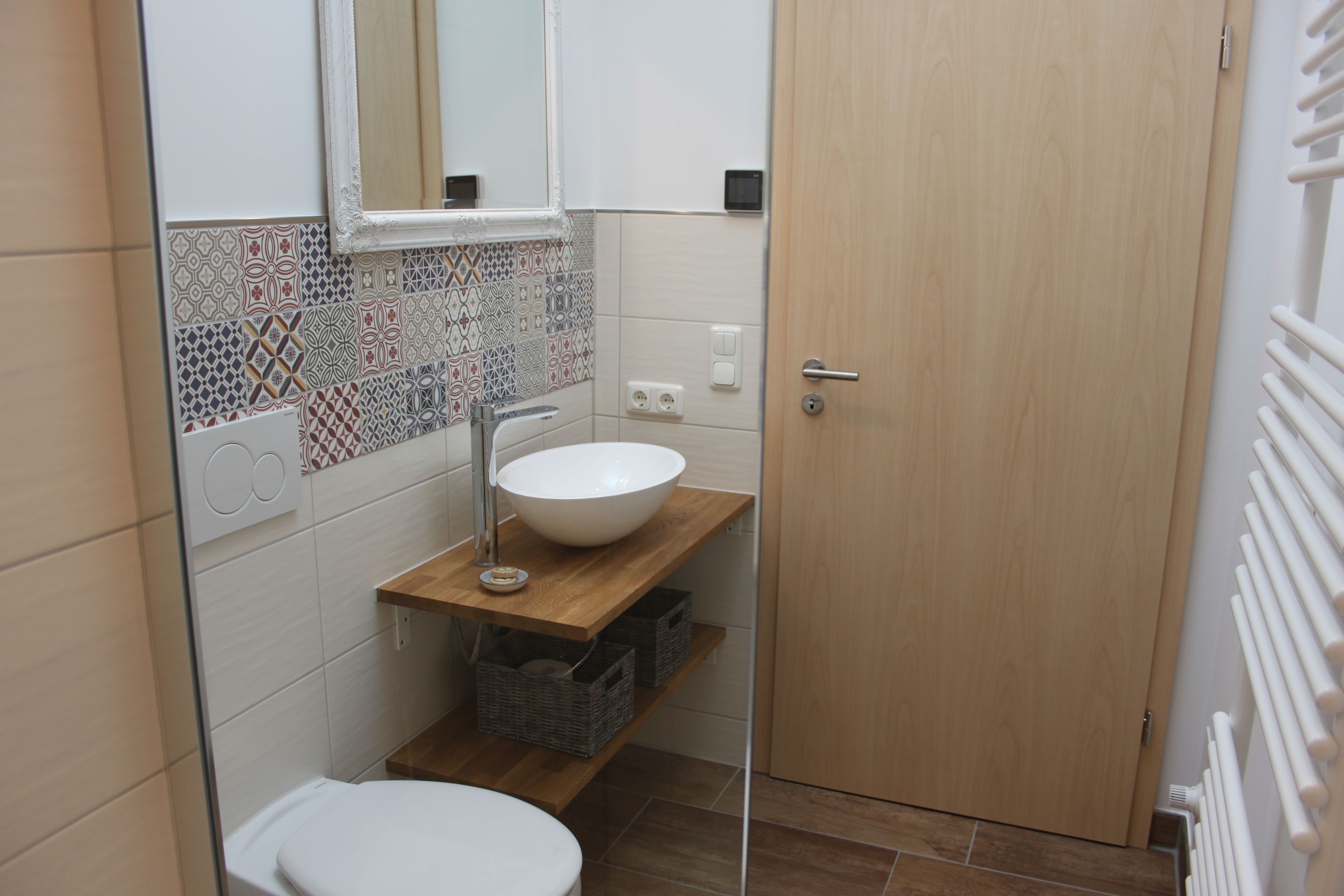 Ein kleines Badezimmer mit einem weißen Waschbecken, einem Spiegel und einer Toilette.