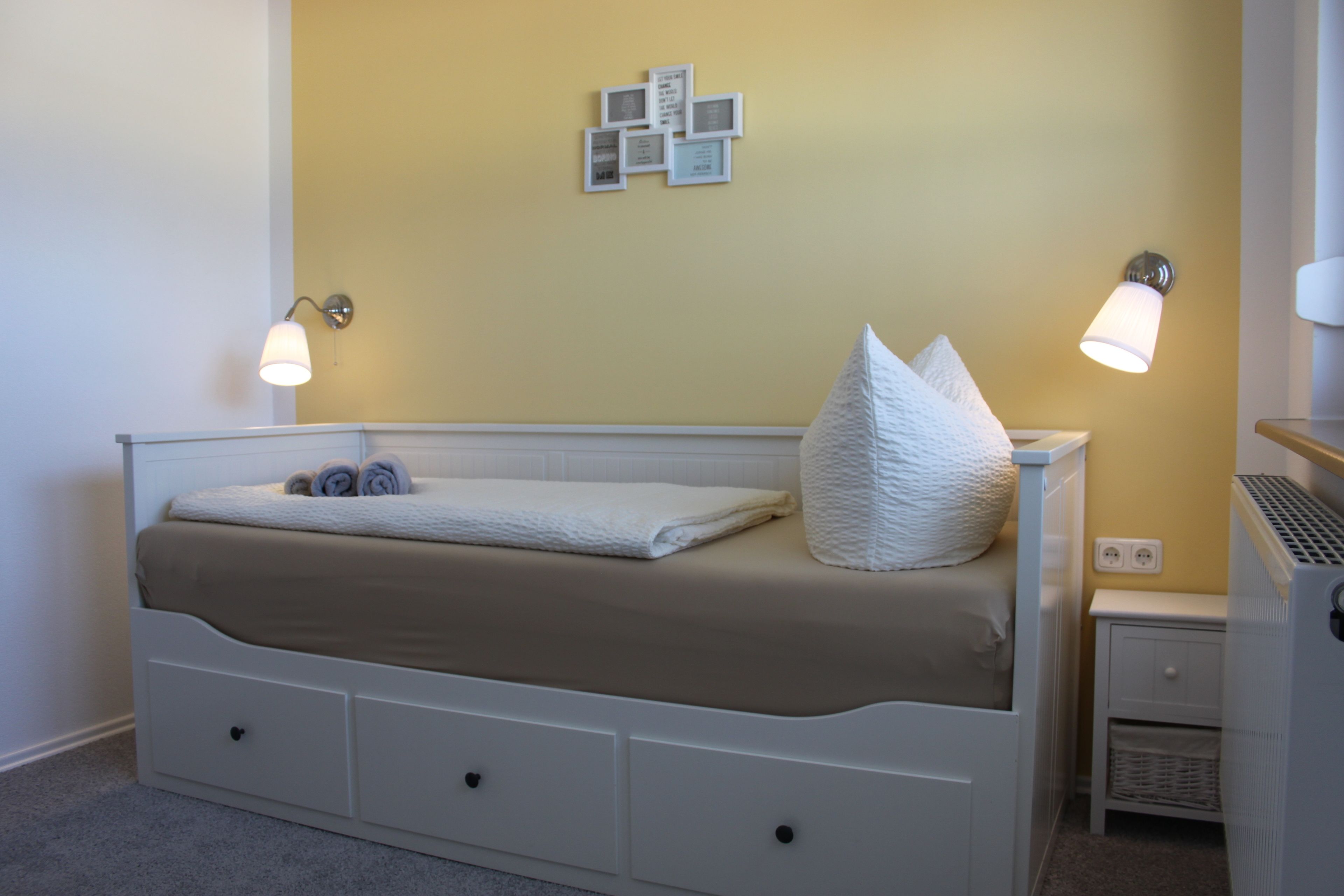 Una camera da letto con un letto, comodini e luci a parete.