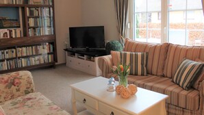 A living room with a sofa, a coffee table, a bookshelf, and a television.