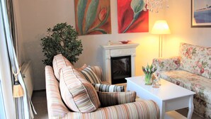 A living room with a striped sofa, a floral sofa, a white coffee table, a fireplace, and a large plant.