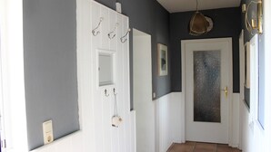 A hallway with a white door, a small window, and a light fixture.