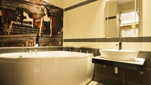 A modern bathroom with a large freestanding bathtub, a wall-mounted sink, and a mirror above the sink. - Myeongpum Drive-in Hotel (Jeongeup)