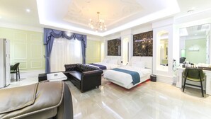 A modern hotel room with a large bed, a sofa, a desk, and a chair. - Myeongpum Drive-in Hotel (Jeongeup)