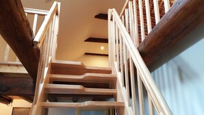 A wooden staircase with white railings and a view of the interior below.