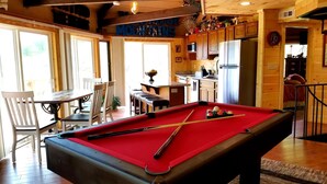 A pool table in a room with wooden beams, a dining area with chairs, and a kitchen area with wooden cabinets. - Mountain View/2 King Suites/Hot Tub/Pool Table/Minutes to Ober & Downtown (Gatlinburg)