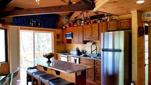 A kitchen with wooden cabinets, a stainless steel refrigerator, and a bar area with stools. - Mountain View/2 King Suites/Hot Tub/Pool Table/Minutes to Ober & Downtown (Gatlinburg)