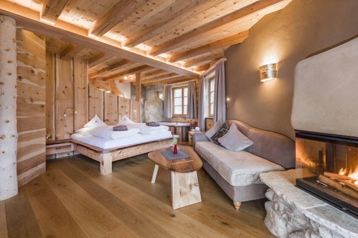 L’intérieur d’un chalet confortable, avec un lit, un canapé et une cheminée.