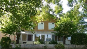 A two-story house with a balcony, surrounded by trees and a stone wall. - Country home (Roquefort)