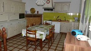 A kitchen with a dining table, chairs, cabinets, a microwave, a sink, and a toaster. - Country home (Roquefort)
